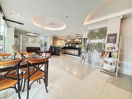 A modern hotel lobby with a reception desk, seating area, and a decorative wall with plants.