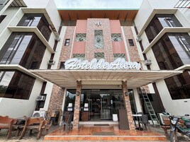 A hotel entrance with a modern facade, large windows, and a covered outdoor seating area.