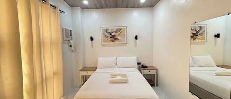 Una habitación de hotel moderna con una cama grande, mesitas de noche, un espejo y obras de arte en las paredes.