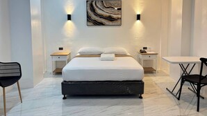 A modern hotel room with a large bed, two bedside tables, a desk, and a chair. - Hotel De Alexa (Maramag)