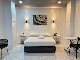 A modern hotel room with a large bed, two bedside tables, a desk, and a chair.