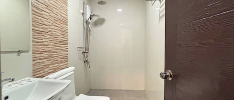A modern bathroom with a shower, toilet, and sink.