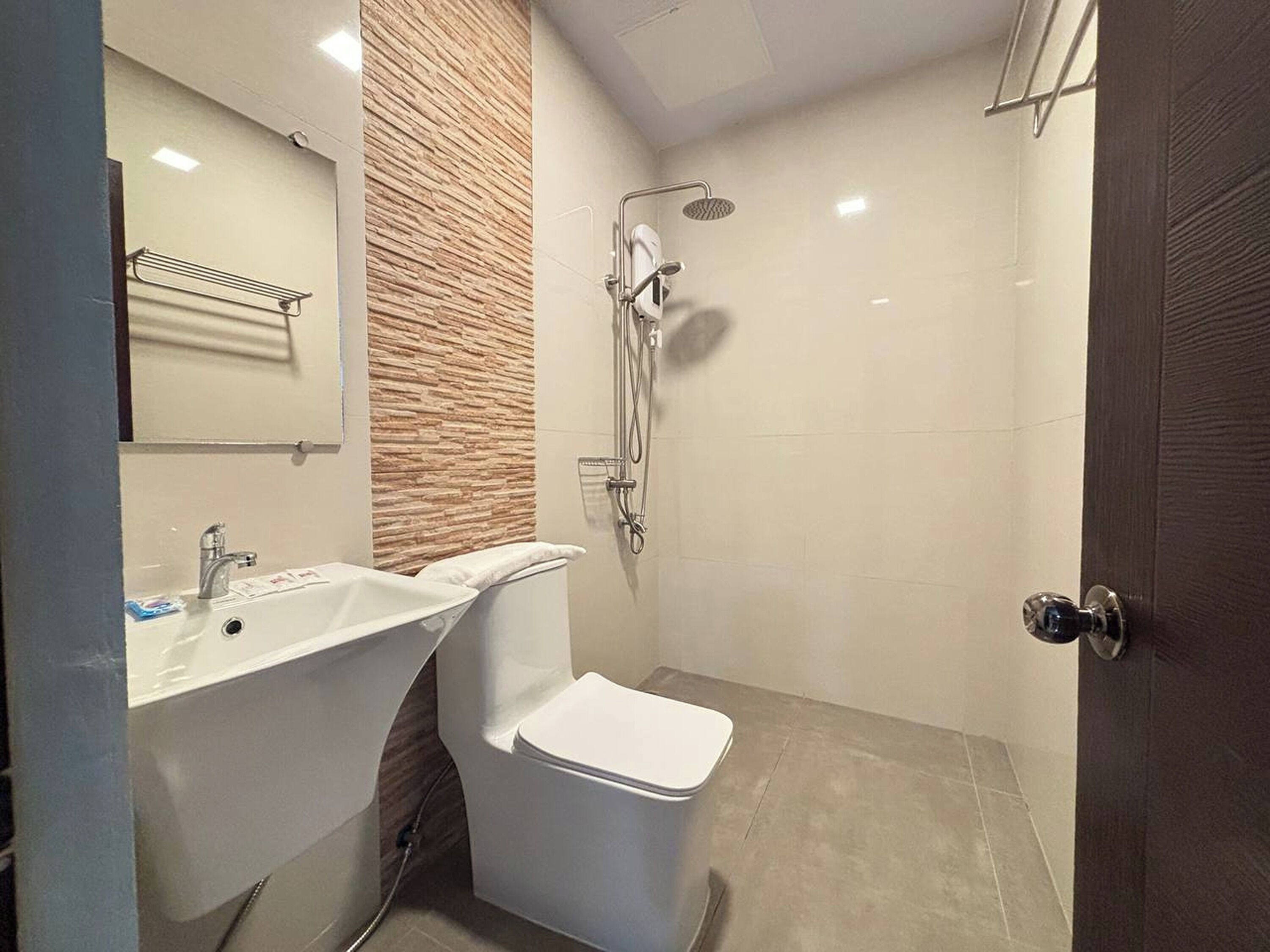 Egy modern fürőszoba mosdókagylóval, WC-vel és zuhanyzóval.