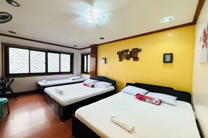 A hotel room with two beds, a desk, and a window with blinds. - Mountain Transient Lodge (Baguio)