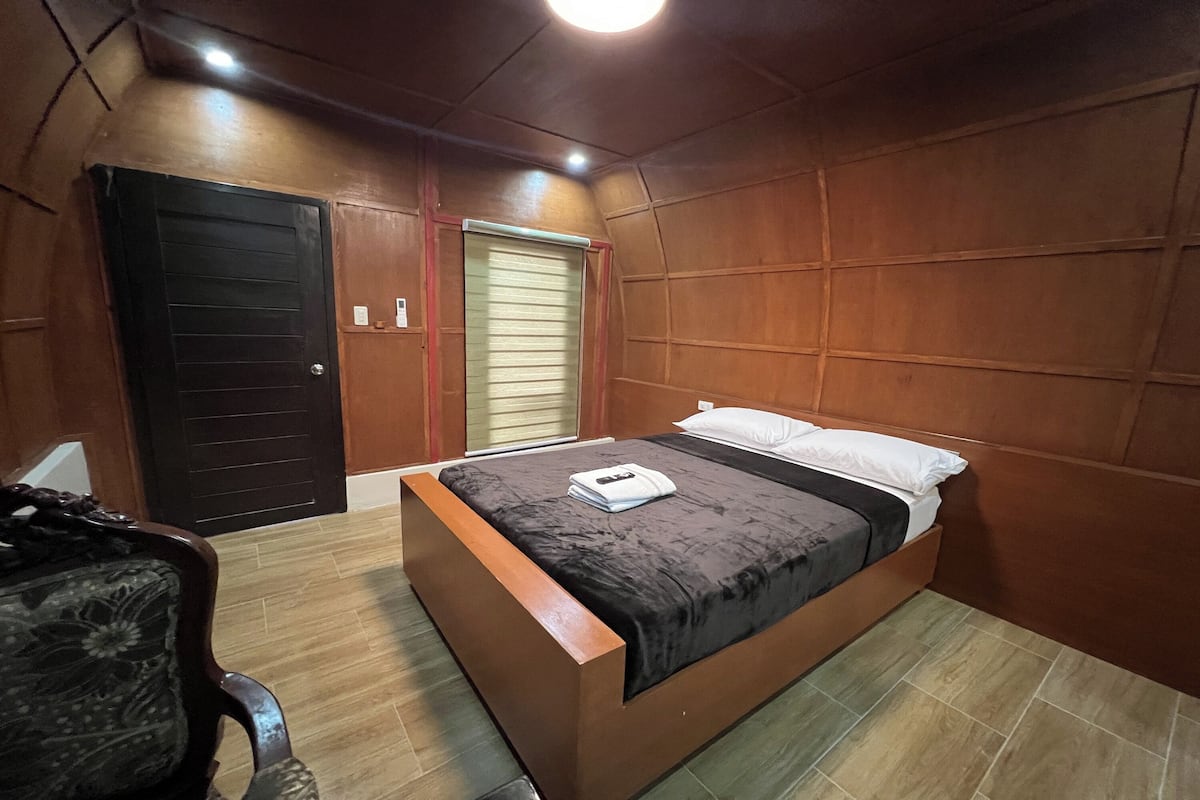 A bedroom with a bed, a chair, a door, and a window.