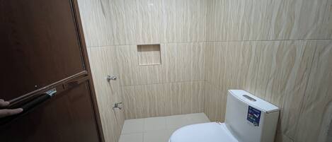 Un bagno con il water, una doccia e un piccolo ripiano.