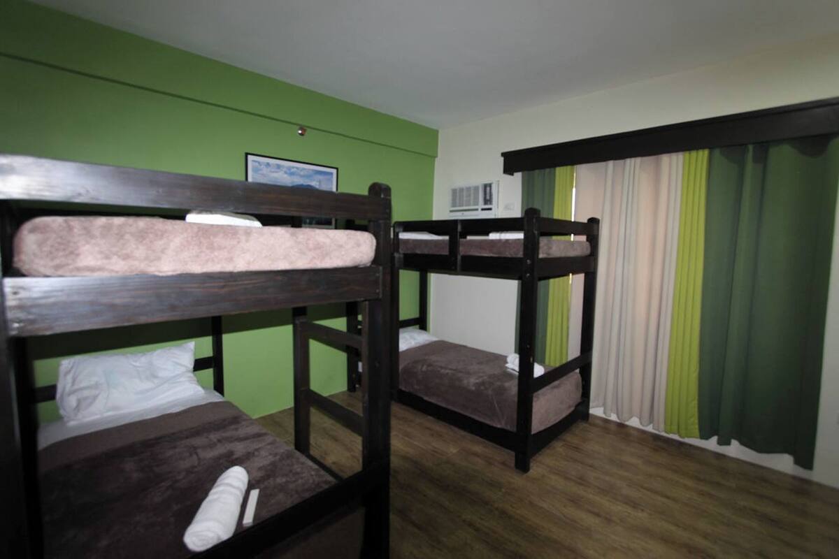 A room with bunk beds, a framed picture on the wall, and a window with curtains.