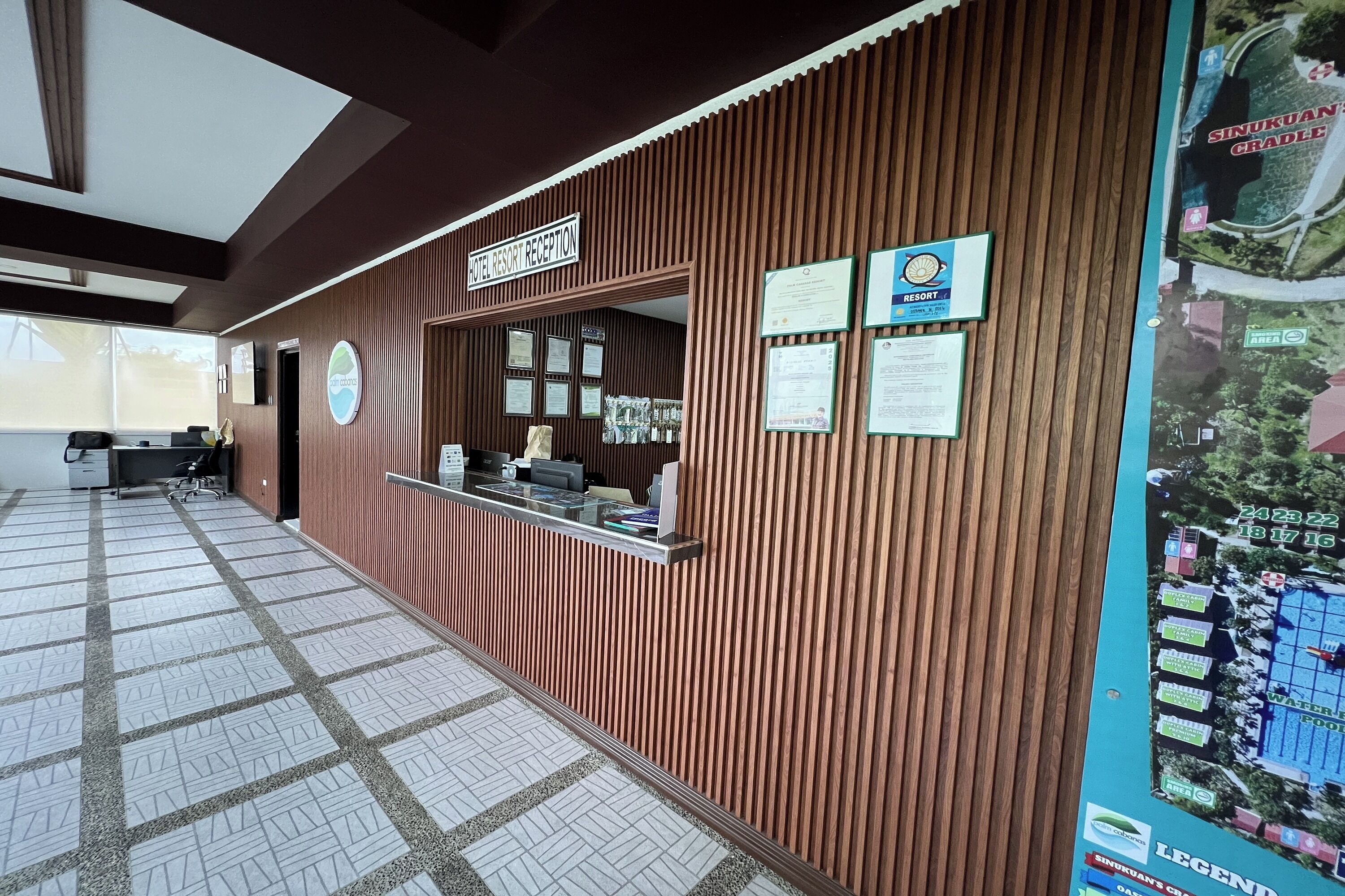 A reception desk with a wooden panel design, a sign indicating the reception area, and several framed certificates on the wall.