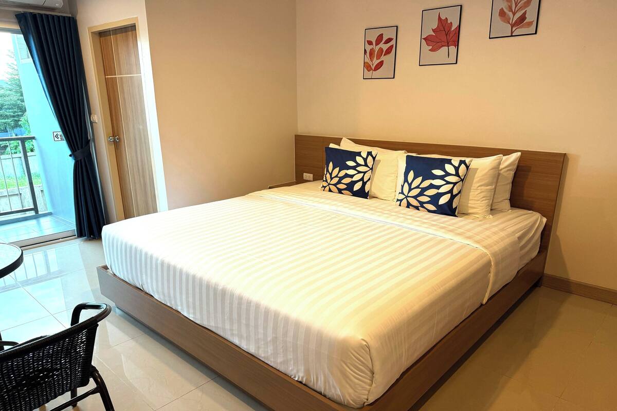 Ein Hotelzimmer mit einem großen Bett, einem Holzkopfende und einem Balkon mit Blick.