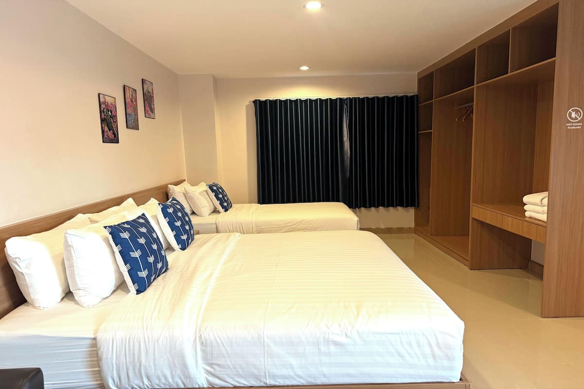 Ein Hotelzimmer mit zwei Betten, einem Kleiderschrank und einem Vorhang.