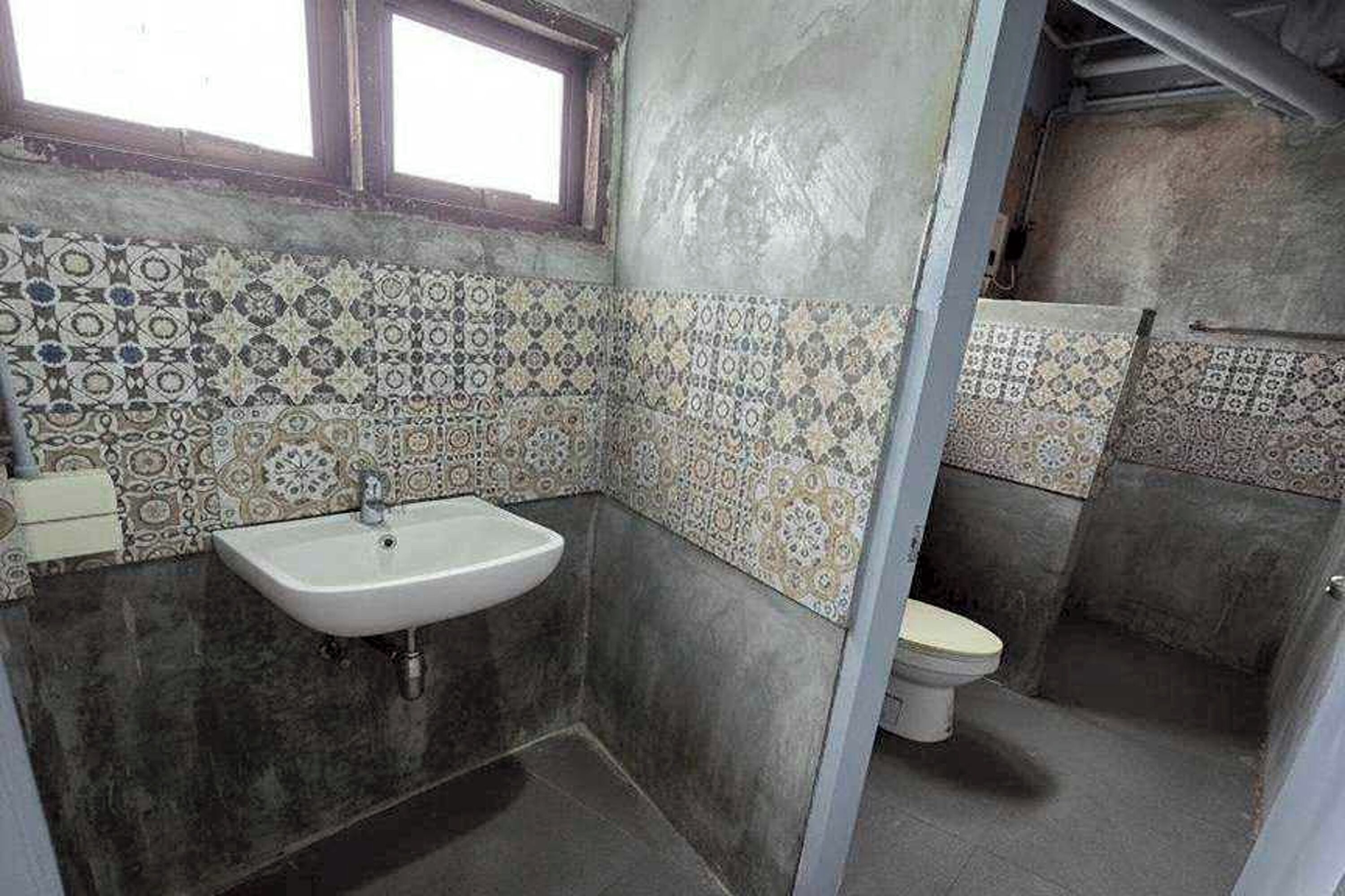 Une salle de bain avec un mur recouvert de carreaux décoratifs, un lavabo et des toilettes.