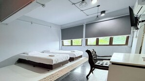 A room with two beds, a desk, and a chair.