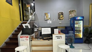 A reception area with a check-in counter, a staircase, and a refrigerator stocked with beverages.