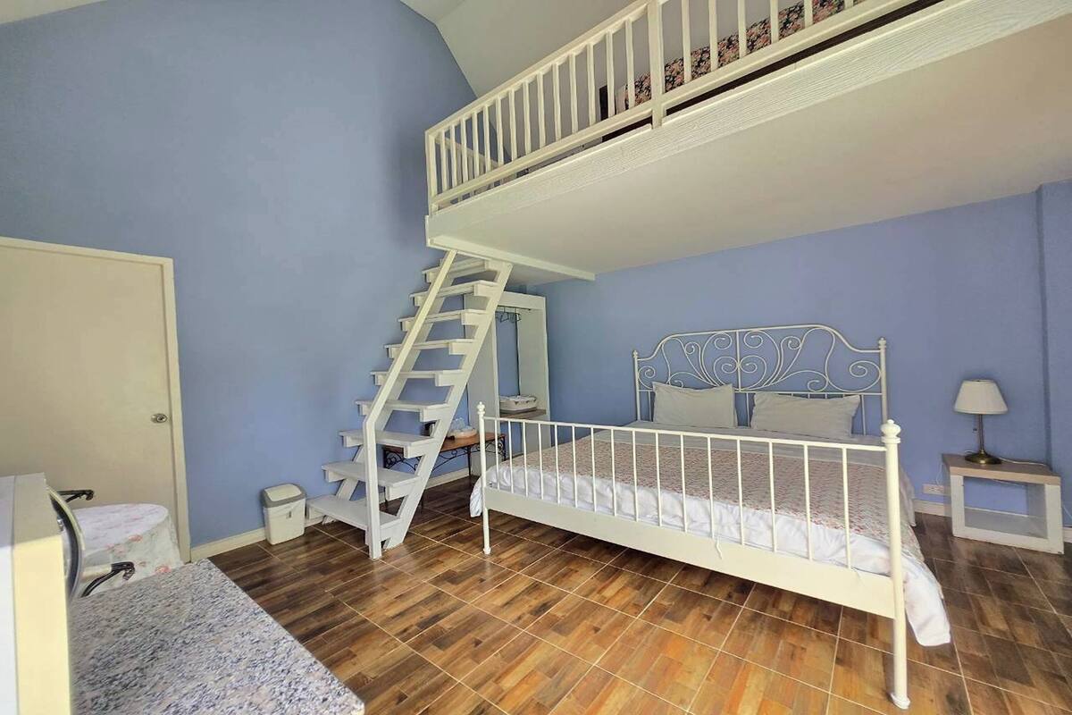 Ein Schlafzimmer mit einem Etagenbett, einer Treppe, einem kleinen Nachttisch und einem Beistelltisch.