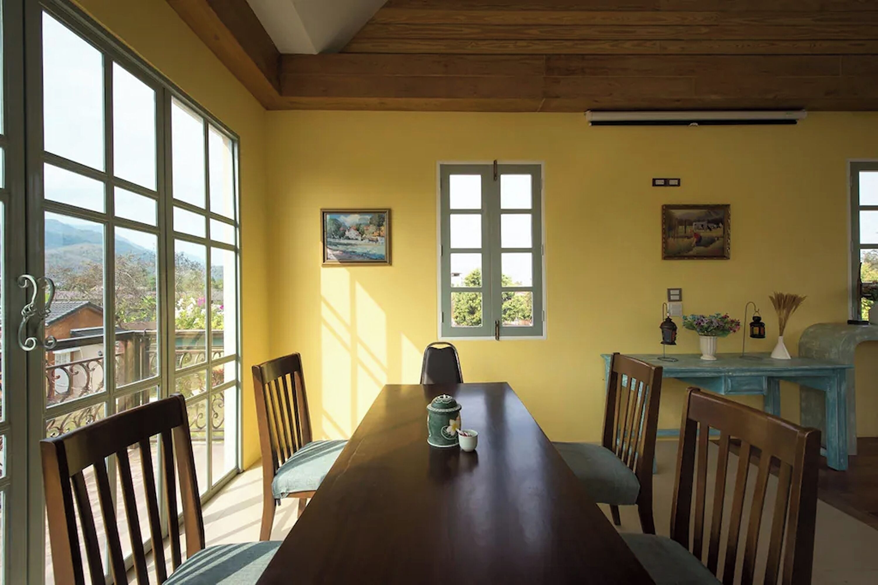 Un espace repas avec une table en bois, des chaises et une vue dégagée grâce à de grandes fenêtres.