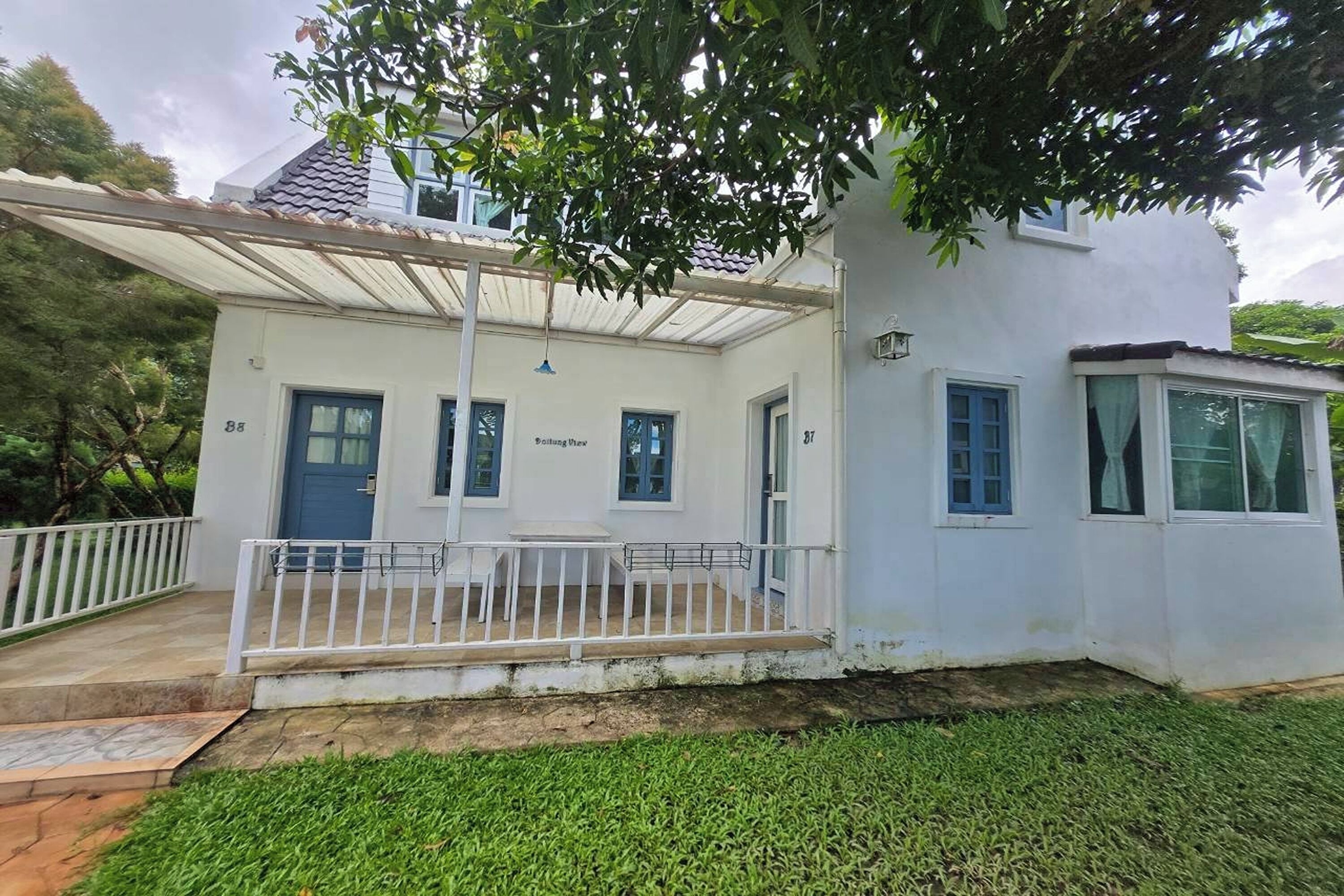 Ein zweistöckiges Haus mit einer Veranda, Hausnummer 87, und ein separates Gebäude mit der Nummer 88.
