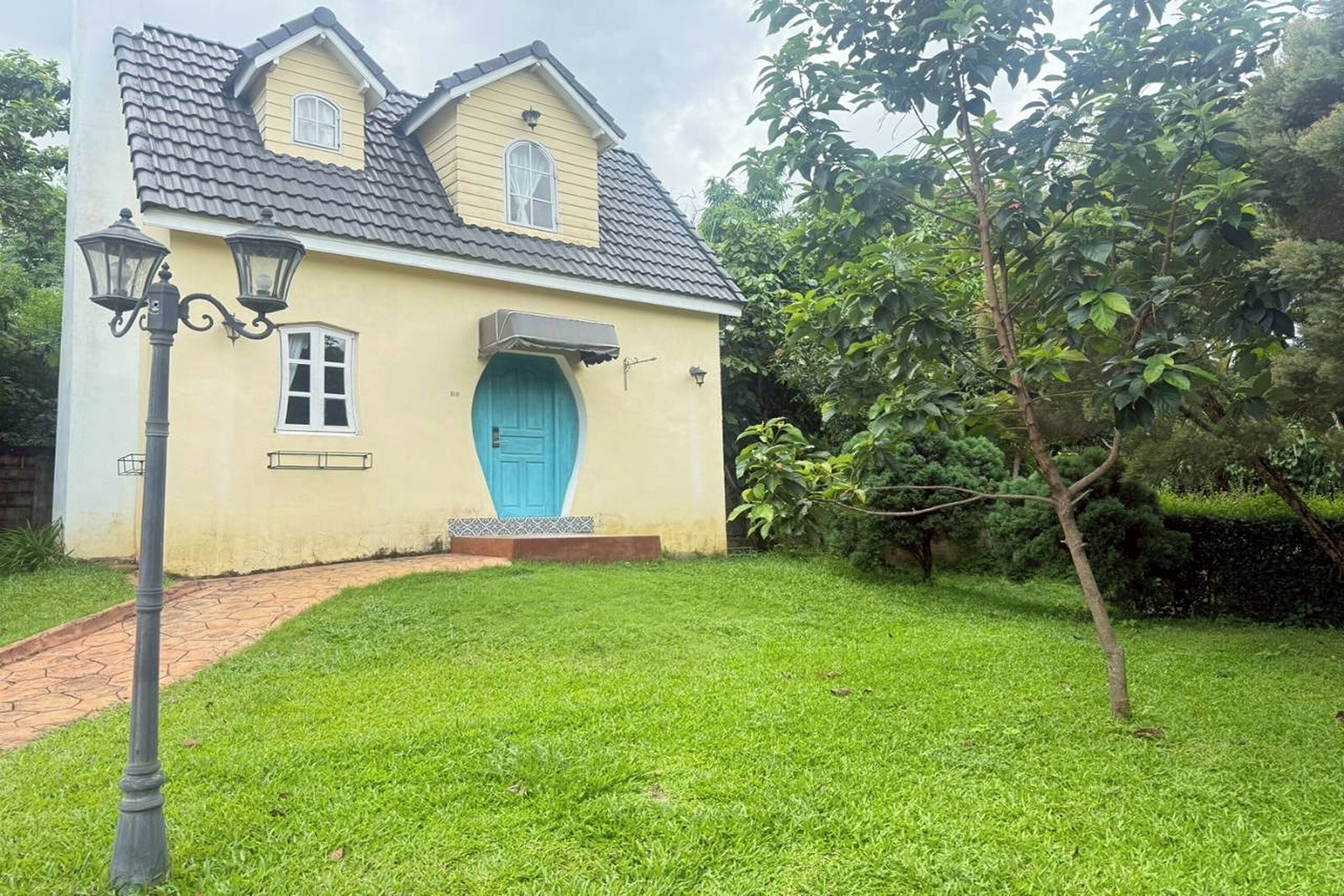 Una casa de dos pisos con una puerta azul y un porche pequeño.