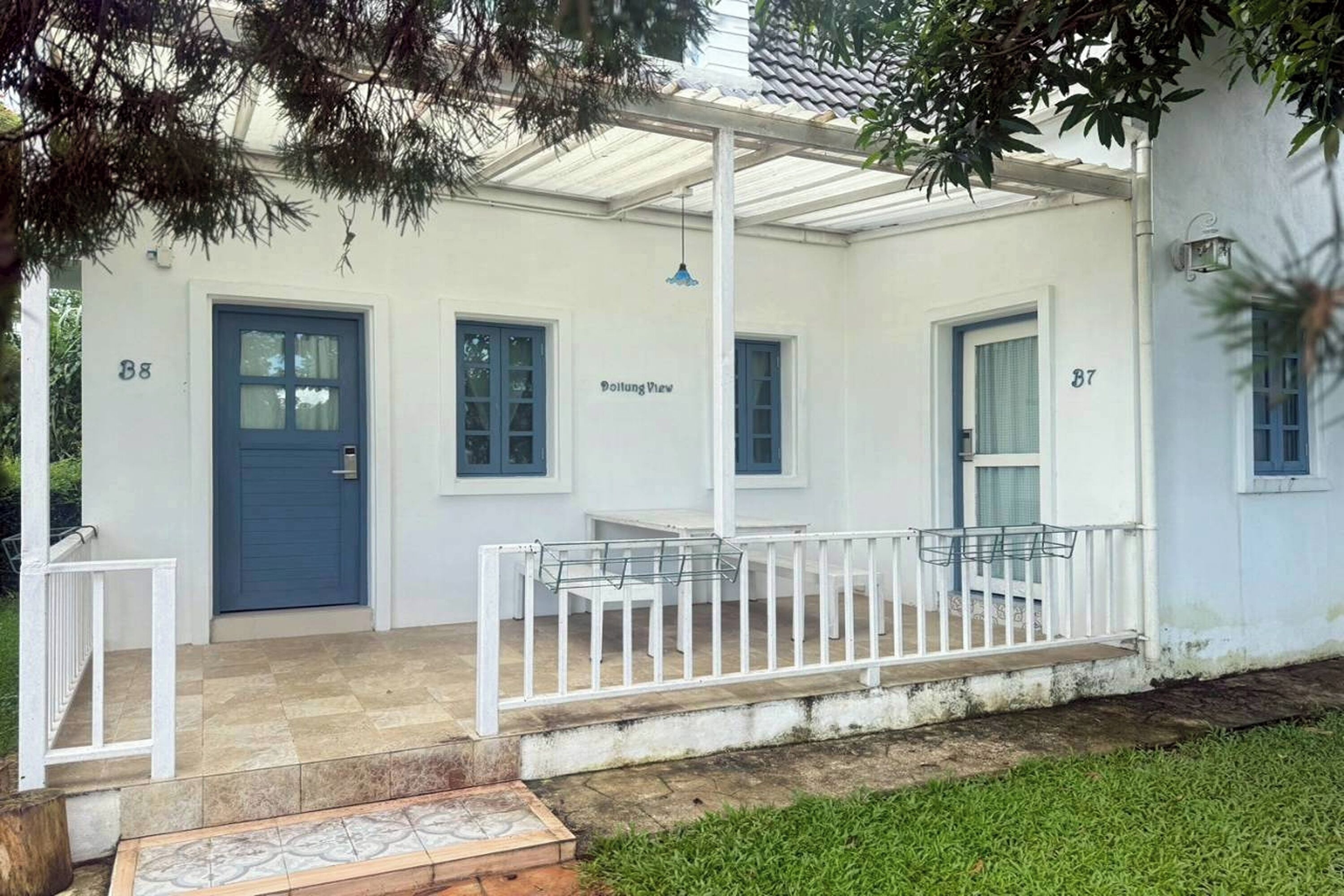 A white building with numbered doors, a covered porch, and a view sign.