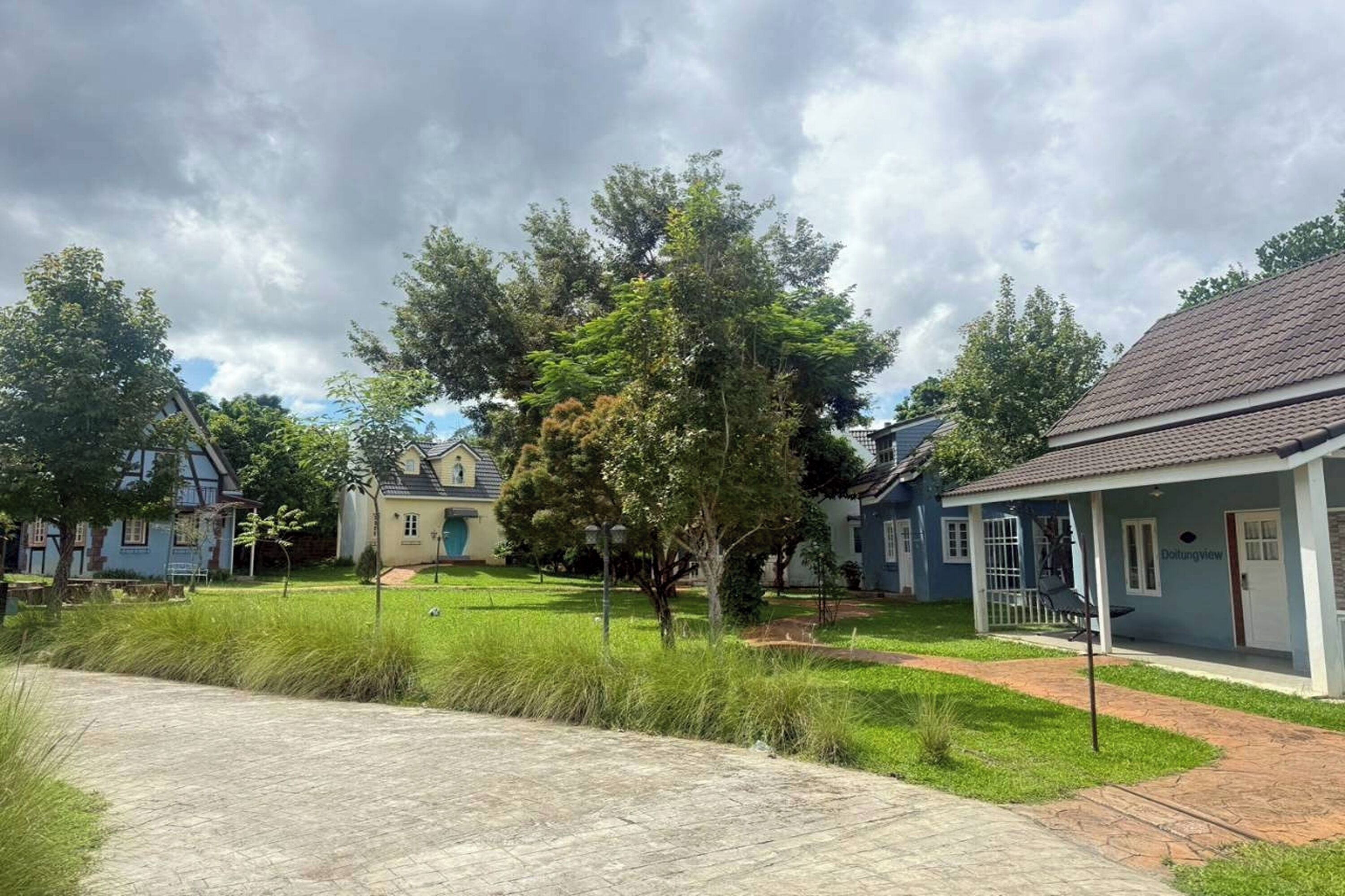 Un quartier résidentiel avec des maisons, un chemin piétonnier pavé et une pelouse.