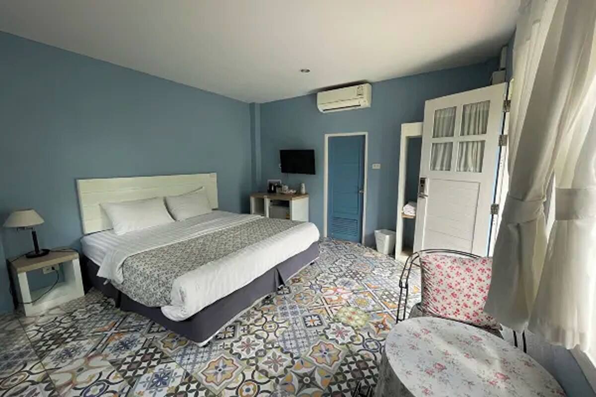 Ein Schlafzimmer mit einem Bett, einem Sessel, einem Fernseher und einer Tür.