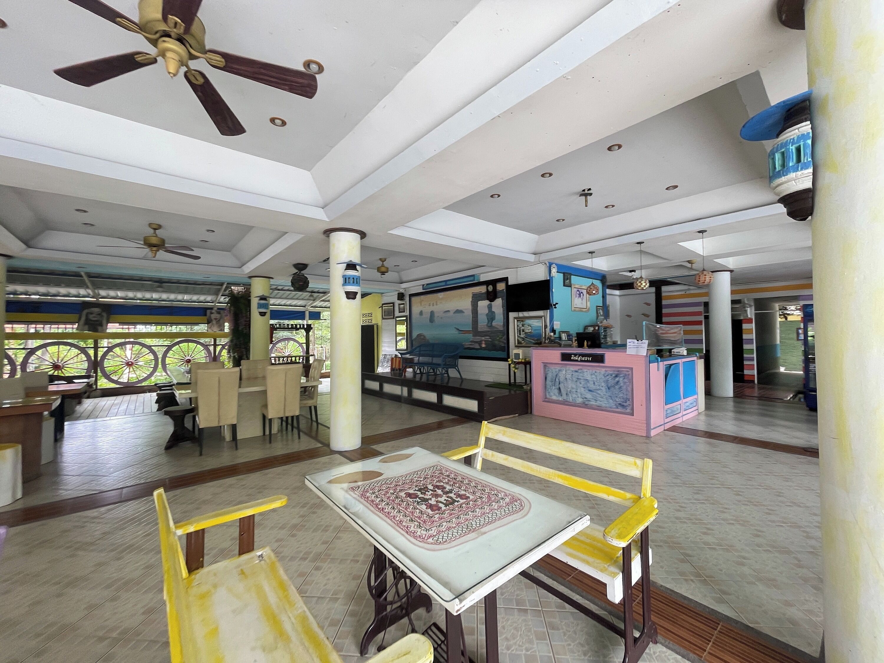 A spacious lobby with a reception desk, seating area, and ceiling fans.