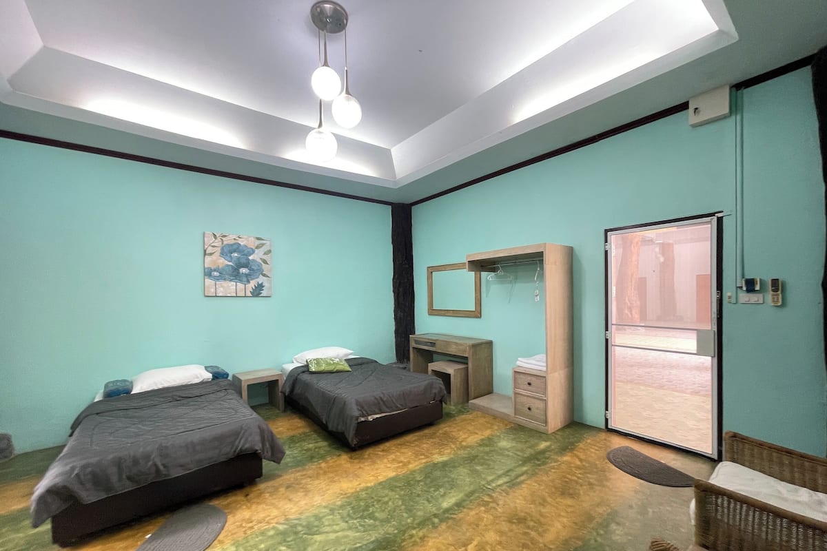 A room with two beds, a desk, a mirror, and a wardrobe.