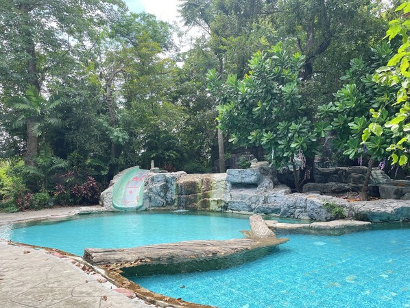 Une piscine d’eau cristalline, entourée de formations rocheuses naturelles et d’une végétation luxuriante.