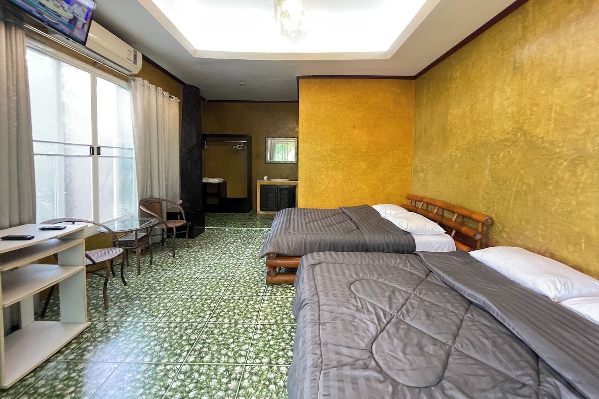 A hotel room with two beds, a desk, a chair, a wardrobe, and a television.