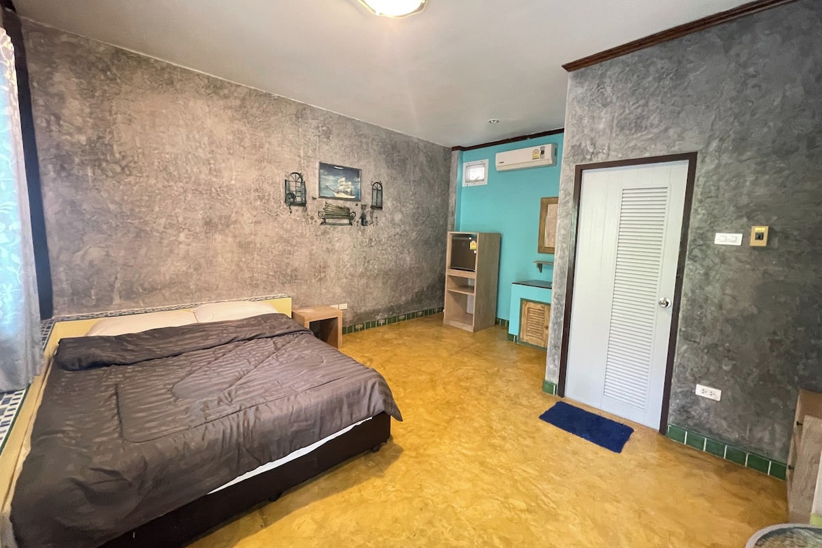 A bedroom with a bed, a small table, a wardrobe, and a door.