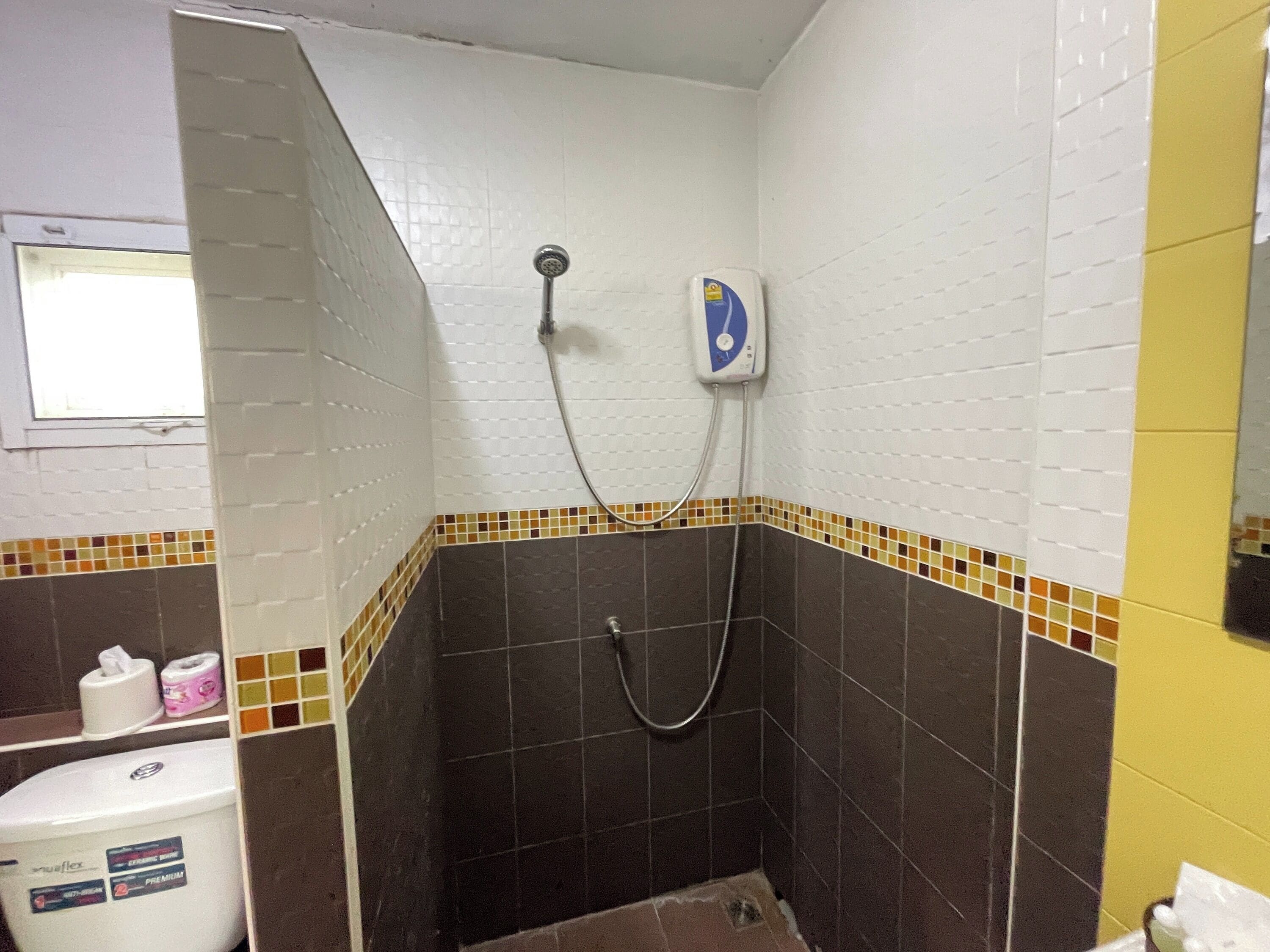 Un baño con ducha, inodoro y espejo.