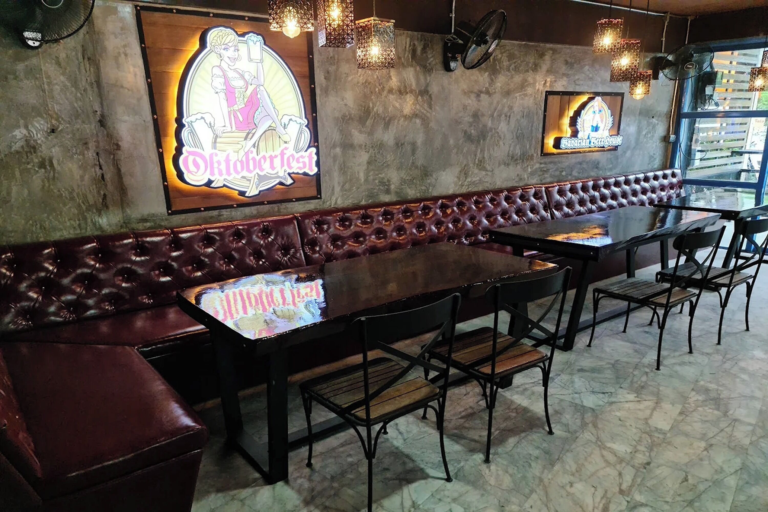 A restaurant interior with a long leather booth, multiple tables, and chairs.