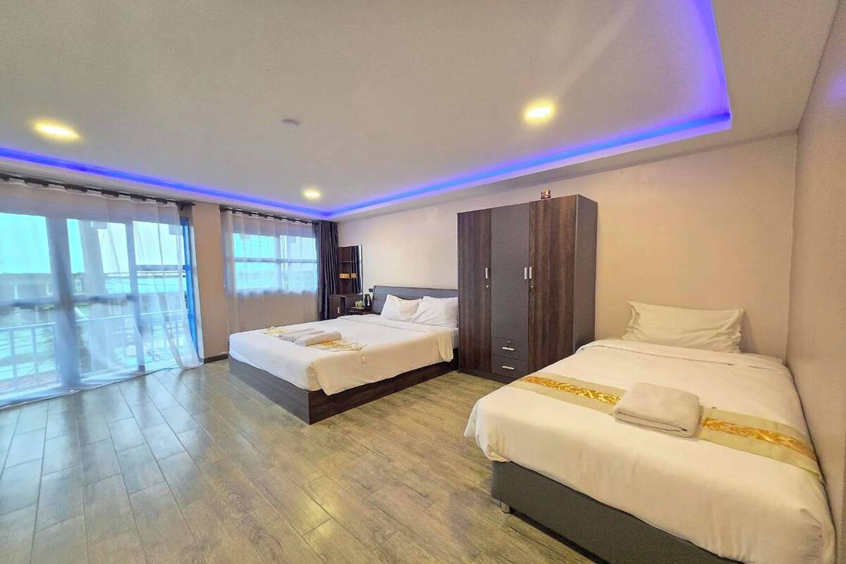 A hotel room with two beds, a wardrobe, and a balcony with curtains.