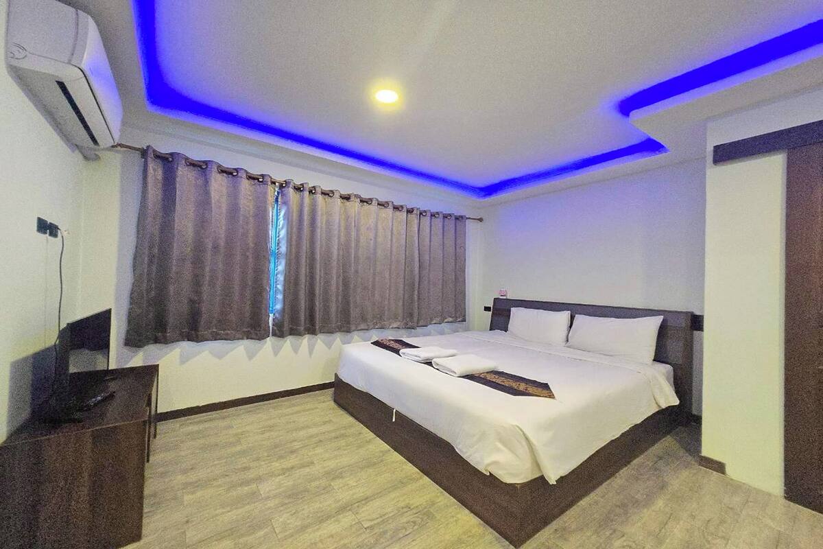 A hotel room with a bed, a desk, and a window with curtains.