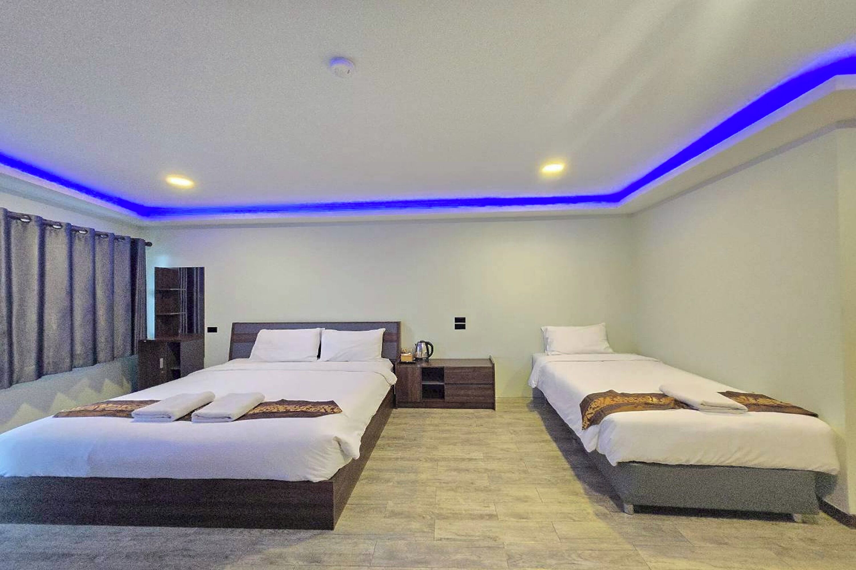 A hotel room with two single beds, a nightstand, a small table, and a window with curtains.