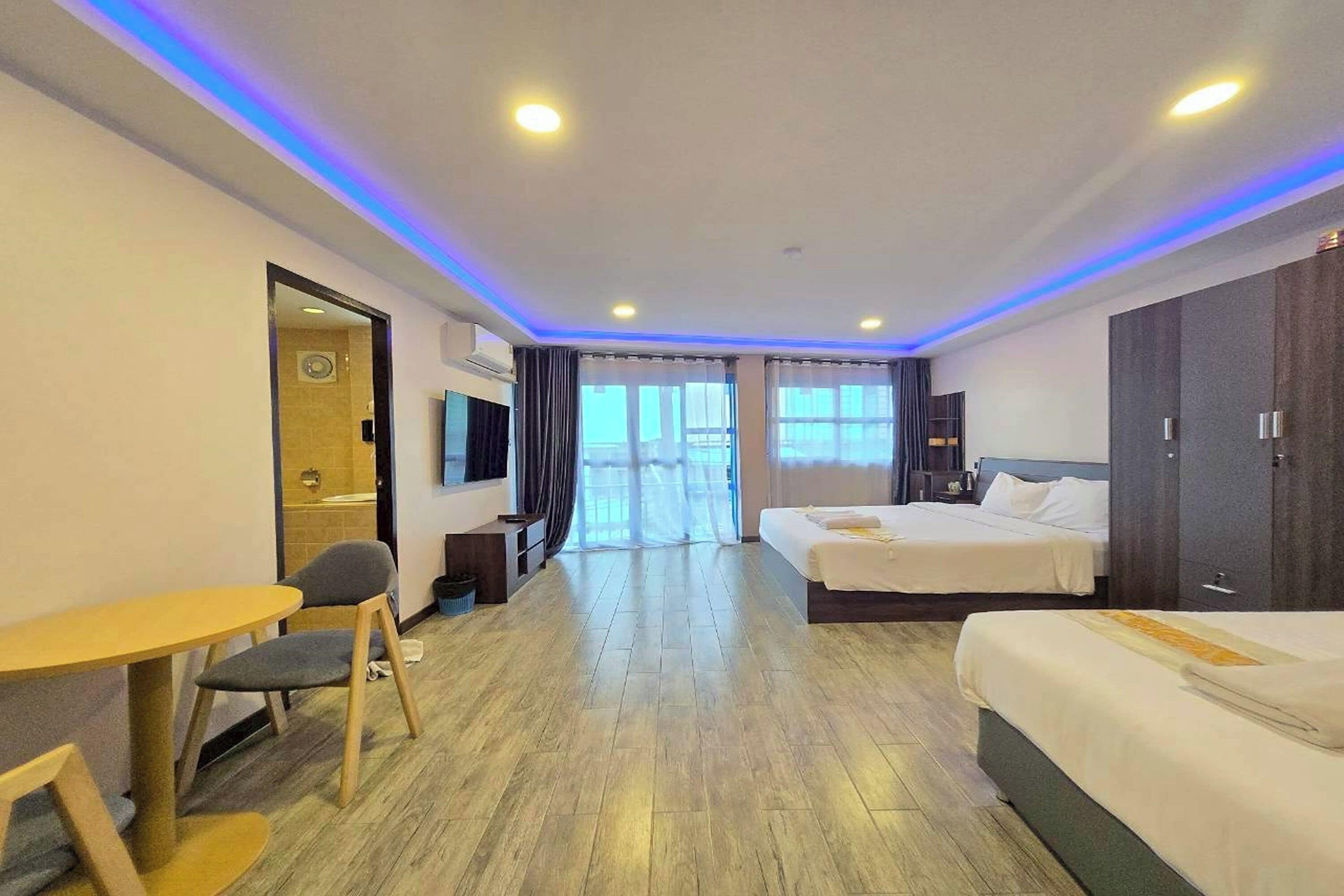 A hotel room with two beds, a desk, a chair, and a TV.