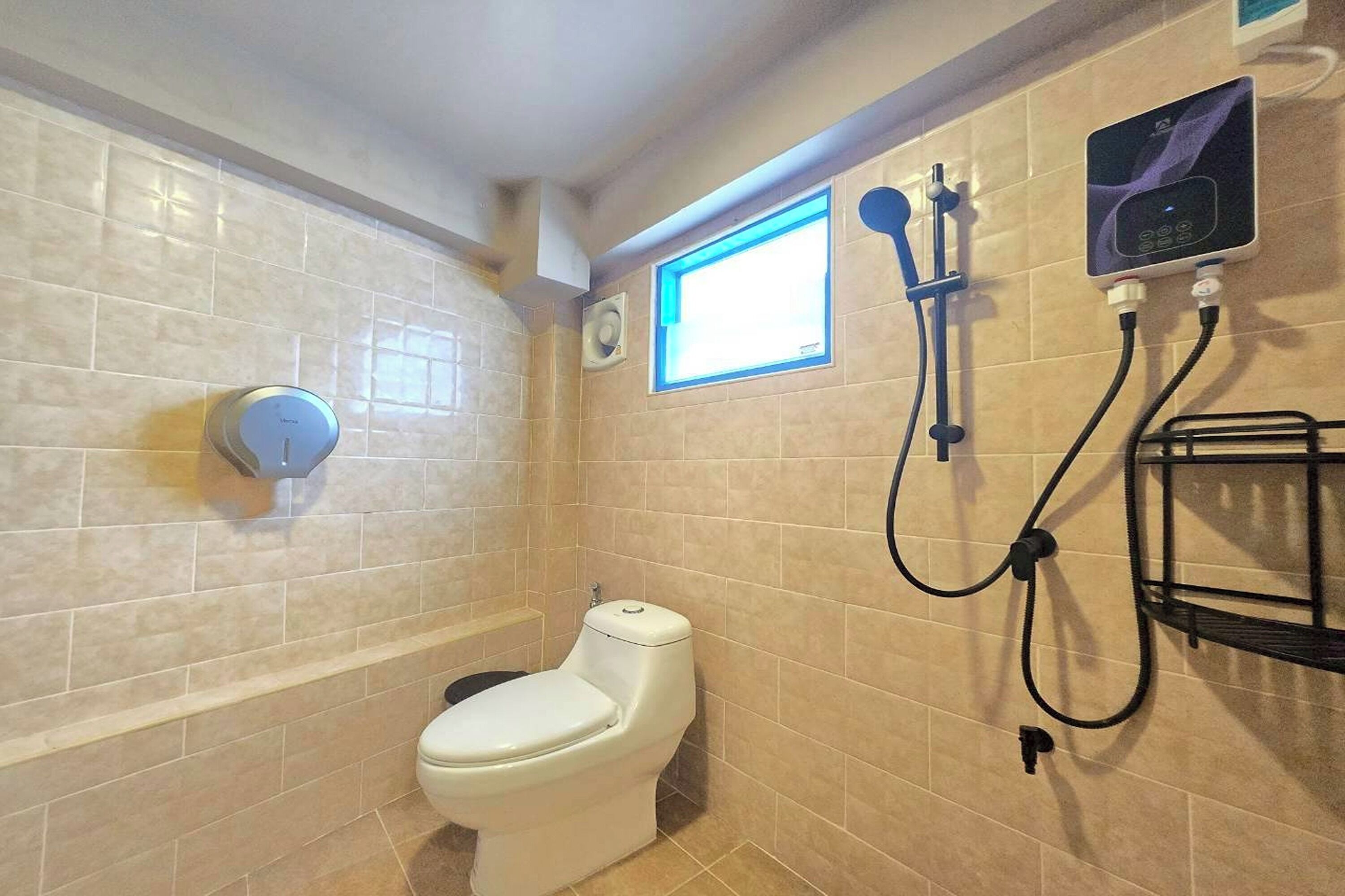 A bathroom with a toilet, a shower with a handheld showerhead, a wall-mounted control panel, and a window.