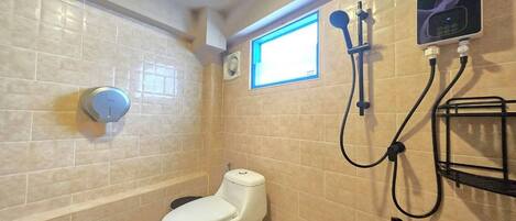 A bathroom with a toilet, a shower with a handheld showerhead, a wall-mounted control panel, and a window.