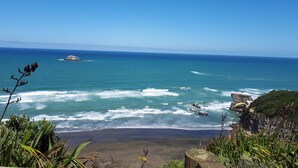 A coastal landscape with a beach, ocean, and rocky cliffs.