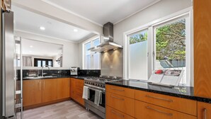 A modern kitchen with wooden cabinets, a stainless steel stove, and a large window providing a view of the outdoors.