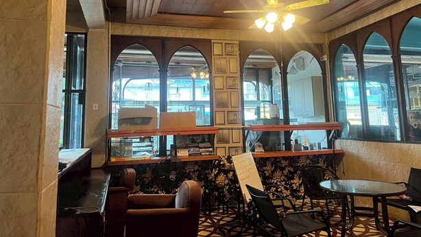 Interior de un restaurante con ventanales arqueados, un ventilador de techo y una zona de bar.