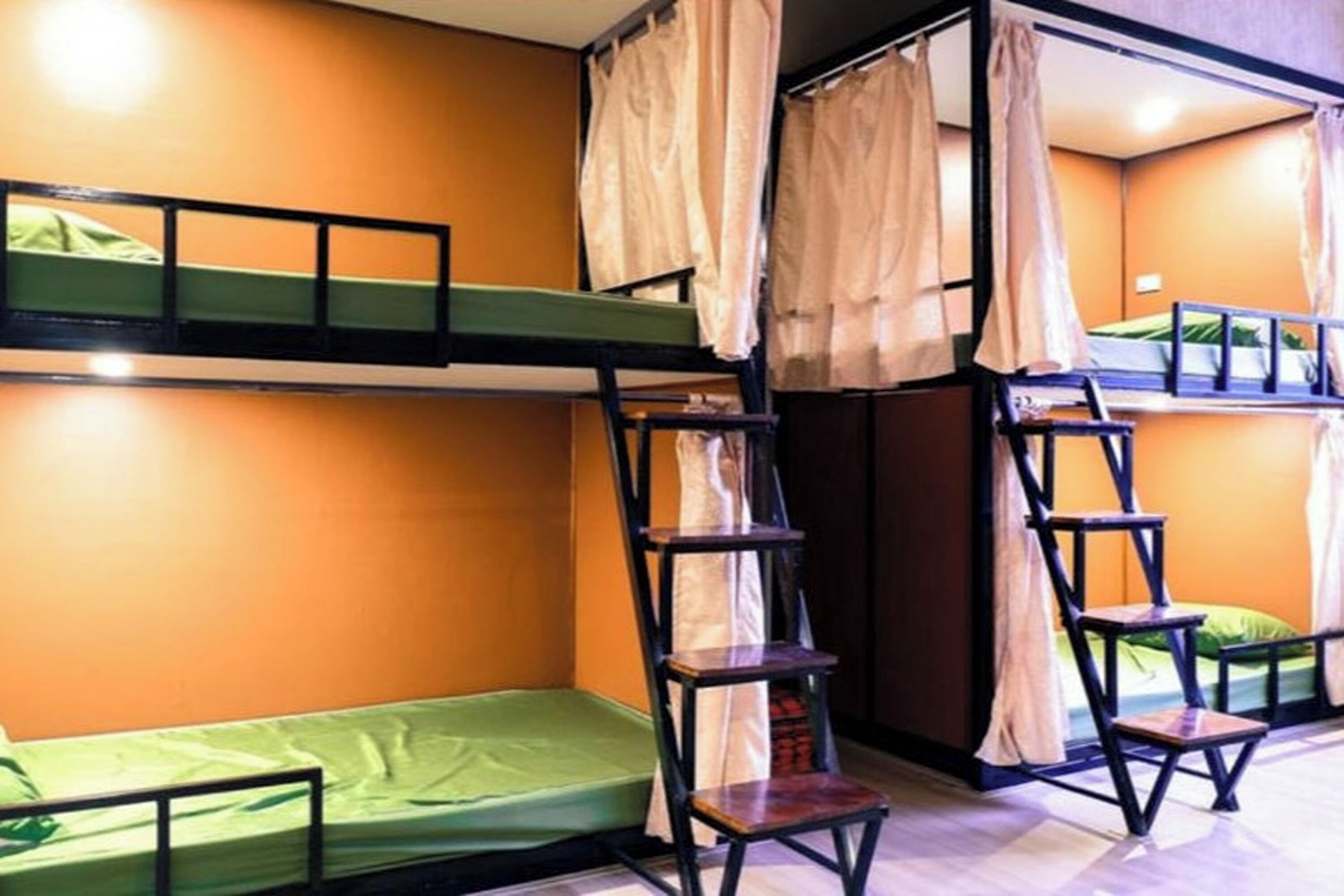 A dormitory room with bunk beds, a ladder, and a chair.