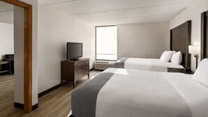 A hotel room with two beds, a television, a desk, and a window.