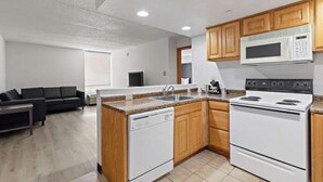 A compact kitchen with a dishwasher, stove, microwave, and wooden cabinets.