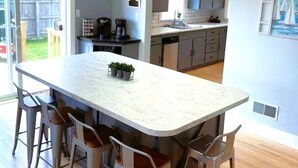 A modern kitchen with a large island, bar stools, and a view of the backyard. - Downtown Algoma - Walk to Beach, Shops, Marina. Easy access to Door County! (Algoma)