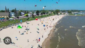A beach with people, kites, and a church in the background. - Downtown Algoma - Walk to Beach, Shops, Marina. Easy access to Door County! (Algoma)