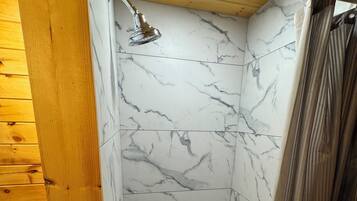 A shower with a marble wall and wooden ceiling.