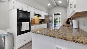 A modern kitchen with white cabinetry, granite countertops, a built-in oven, and a stainless steel refrigerator. - Spacious 5-bedroom house in wonderful Richardson with Arcade Games (Richardson)