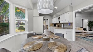 A modern kitchen with white cabinets, a large island, and a dining area with a round table and woven placemats. - Spacious 5-bedroom house in wonderful Richardson with Arcade Games (Richardson)