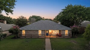 A two-story house with a front porch, a visible garage, and a well-maintained lawn. - Spacious 5-bedroom house in wonderful Richardson with Arcade Games (Richardson)