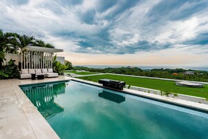 A swimming pool with a view of a lush green lawn and distant buildings.